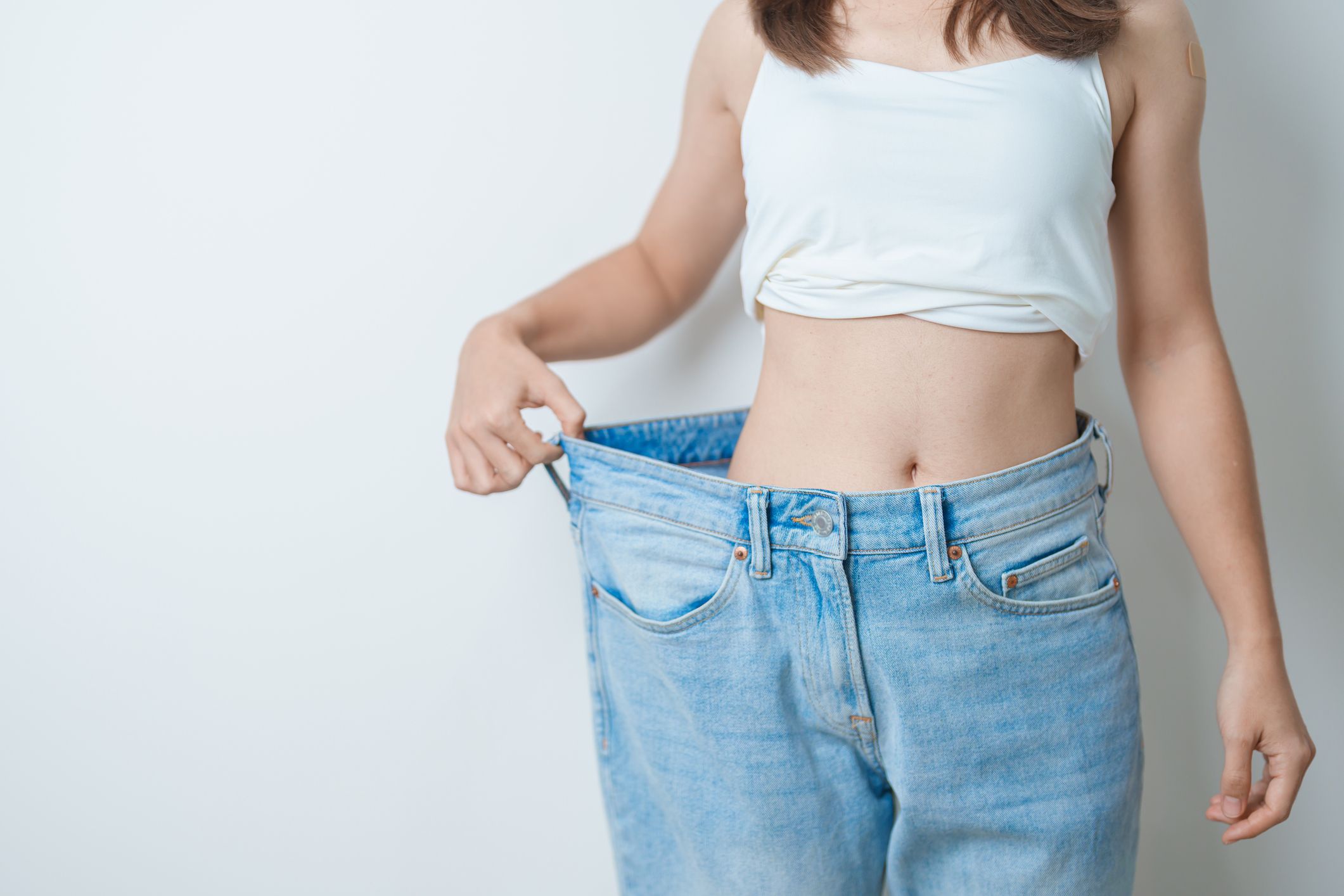 Mujer mostrando sus pantalones después de perder peso